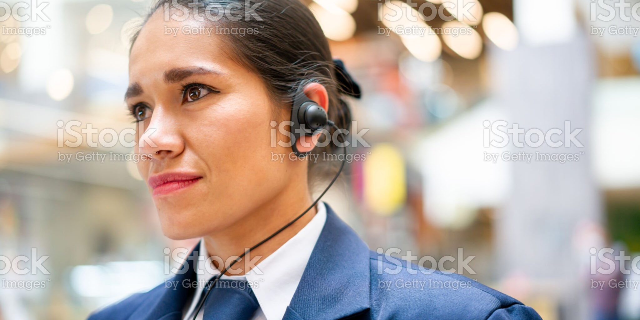 Portrait of a Latin American female security guard working at a shopping mall and wearing a headset